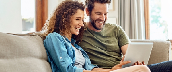 A smiling couple at home using online banking on a tablet